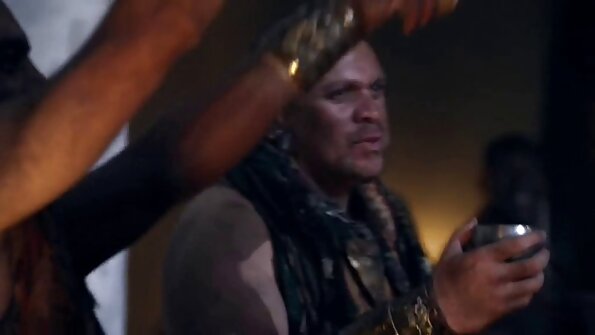 Un amator sexy stă pe nisip, ținând o sticlă la soare